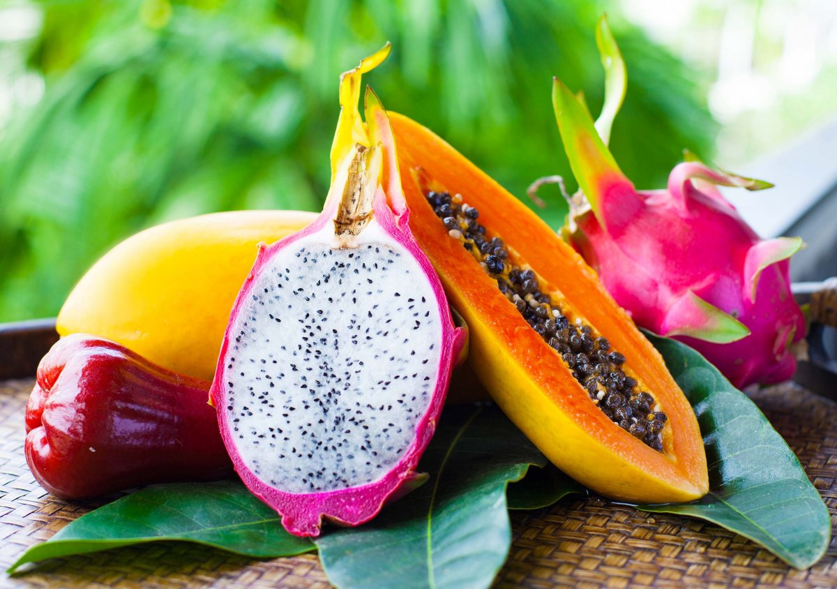 Un agricultor sosteniendo una cesta de frutas tropicales frescas.